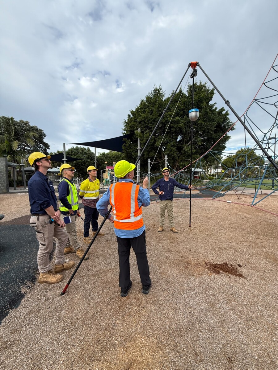 Construction workers inspect playground equipment.