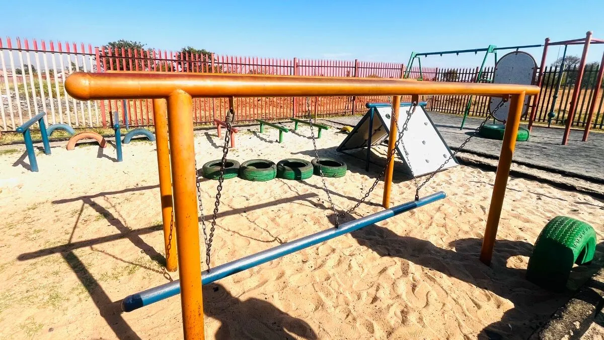 Playground equipment with swings and tires.